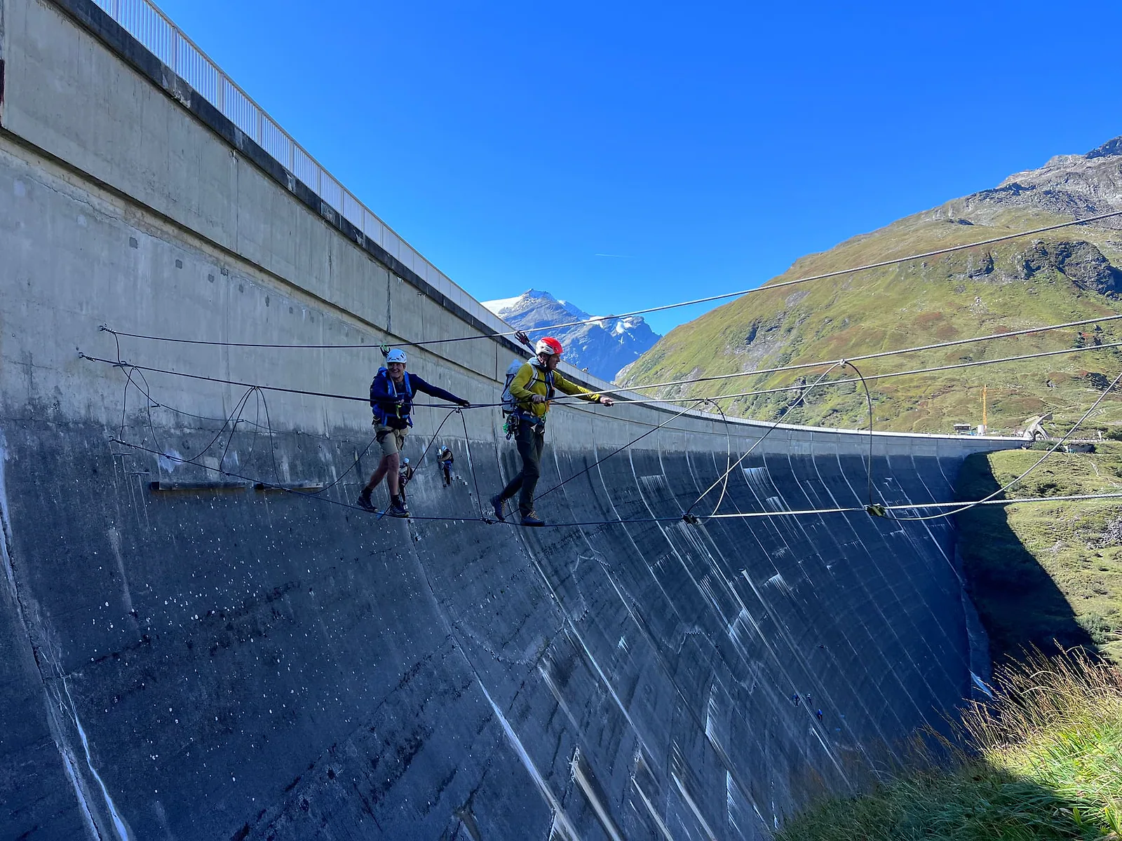 Twee mannen aan een kabel langs de muur van een stuwdam