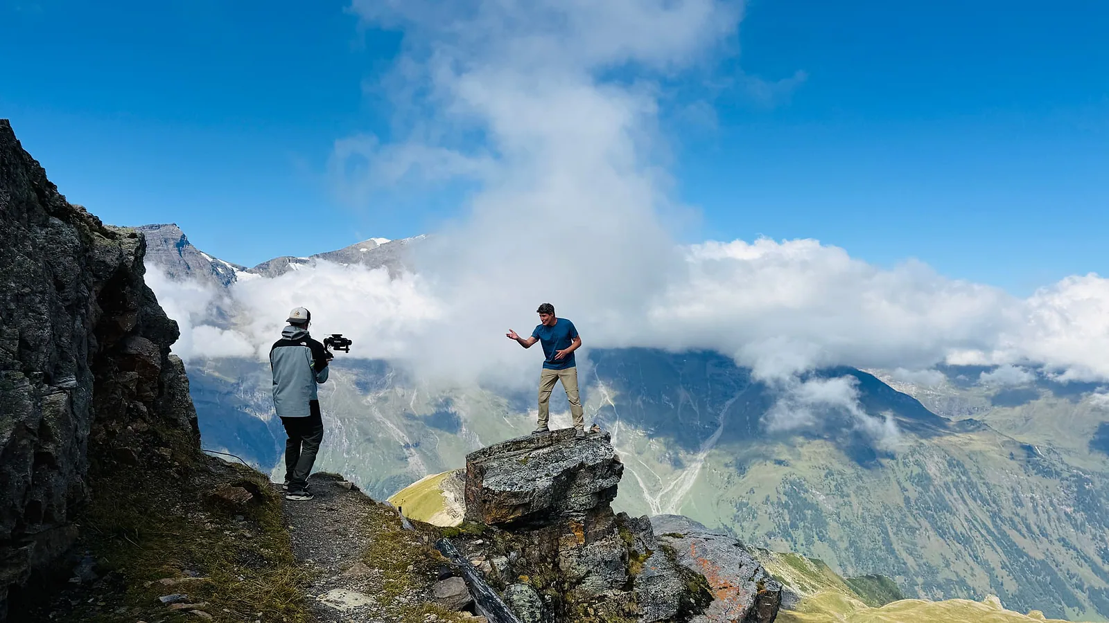 Cameraman filmt de presentator op een rots boven de wolken